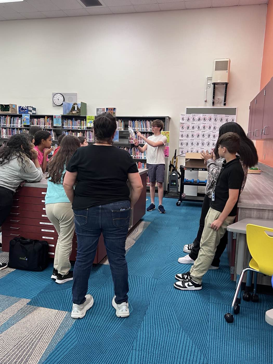 The founder holding up a bottle rocket while explaining the build to a class in a school library.